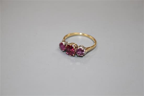 An 18ct and three stone ruby and garnet?? set dress ring, size M, gross 2.7 grams.